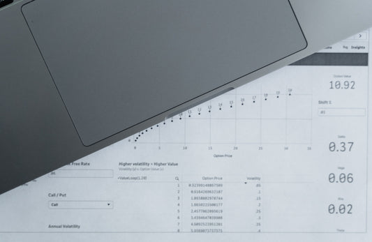 Top-down view of printed data sheets next to a laptop on a desk